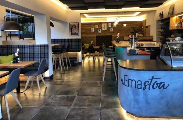 Café Emastoa in Reitdorf - Barbereich mit Tischen, Wandverkleidung, Lampen und Stühlen