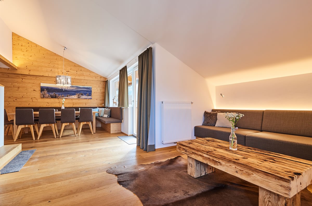 Exklusiver Wohnraum mit Essecke, Couchtisch und Wandverkleidung aus Holz im Aparthotel Central